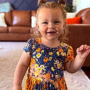 Hadley Dawn is registered to the contest to win money with this photo: child, girl, smiling, portrait, indoor, living_room, dress, floral_pattern, hair_tied, cute, happy, person, fashion, young_child, home, couch, carpet, colorful, standing, playful