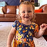 child, girl, smiling, portrait, indoor, living_room, dress, floral_pattern, hair_tied, cute, happy, person, fashion, young_child, home, couch, carpet, colorful, standing, playful
