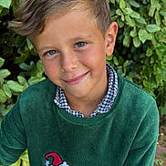Antoine a rejoint le concours — aidez-le/la à gagner de superbes lots ! child, boy, smile, green_sweater, the_grinch, leafy_background, outdoor, freckled_face, short_hair, portrait, casual_clothing, happy, nature, wooden_deck, young, cute, fashion, holiday_theme, playful, closeup