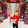 Graylen is registered to the contest to win money with this photo: child, kid, boy, gift, present, red_sweater, santa_claus, holiday, christmas, north_pole, snowman, wreath, decorations, festive, winter, indoors, background, smile, boots, celebration