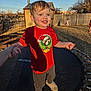 Graylen joined the competition — help win amazing prizes! toddler, child, trampoline, red_shirt, smile, outdoor, backyard, fence, grass, sunlight, shadow, person, holding_hand, play, casual_clothing, footwear, happy, daytime, tree, young_child