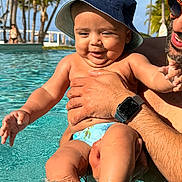 Angel joined the competition — help win amazing prizes! baby, child, man, pool, water, splashing, sunny, hat, bucket_hat, swim_diaper, palm_trees, outdoor, summer, vacation, happy, smiling, adult, sunglasses, watch, skin