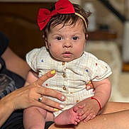 Myanna a rejoint le concours — aidez-le/la à gagner de superbes lots ! adult_hand, baby, buttoned_shirt, child, clothing, cute, expression, fingernails, foot, hand, headband, holding, indoor, person, portrait, red_bow, sitting, skin, toes, yellow_nail_polish