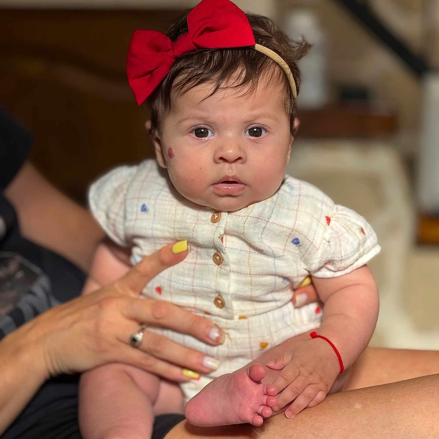 Myanna a rejoint le concours — aidez-le/la à gagner de superbes lots ! adult_hand, baby, buttoned_shirt, child, clothing, cute, expression, fingernails, foot, hand, headband, holding, indoor, person, portrait, red_bow, sitting, skin, toes, yellow_nail_polish