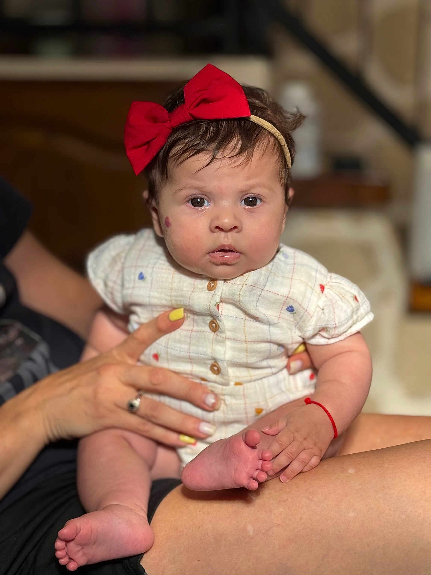 Myanna a rejoint le concours — aidez-le/la à gagner de superbes lots ! adult_hand, baby, buttoned_shirt, child, clothing, cute, expression, fingernails, foot, hand, headband, holding, indoor, person, portrait, red_bow, sitting, skin, toes, yellow_nail_polish