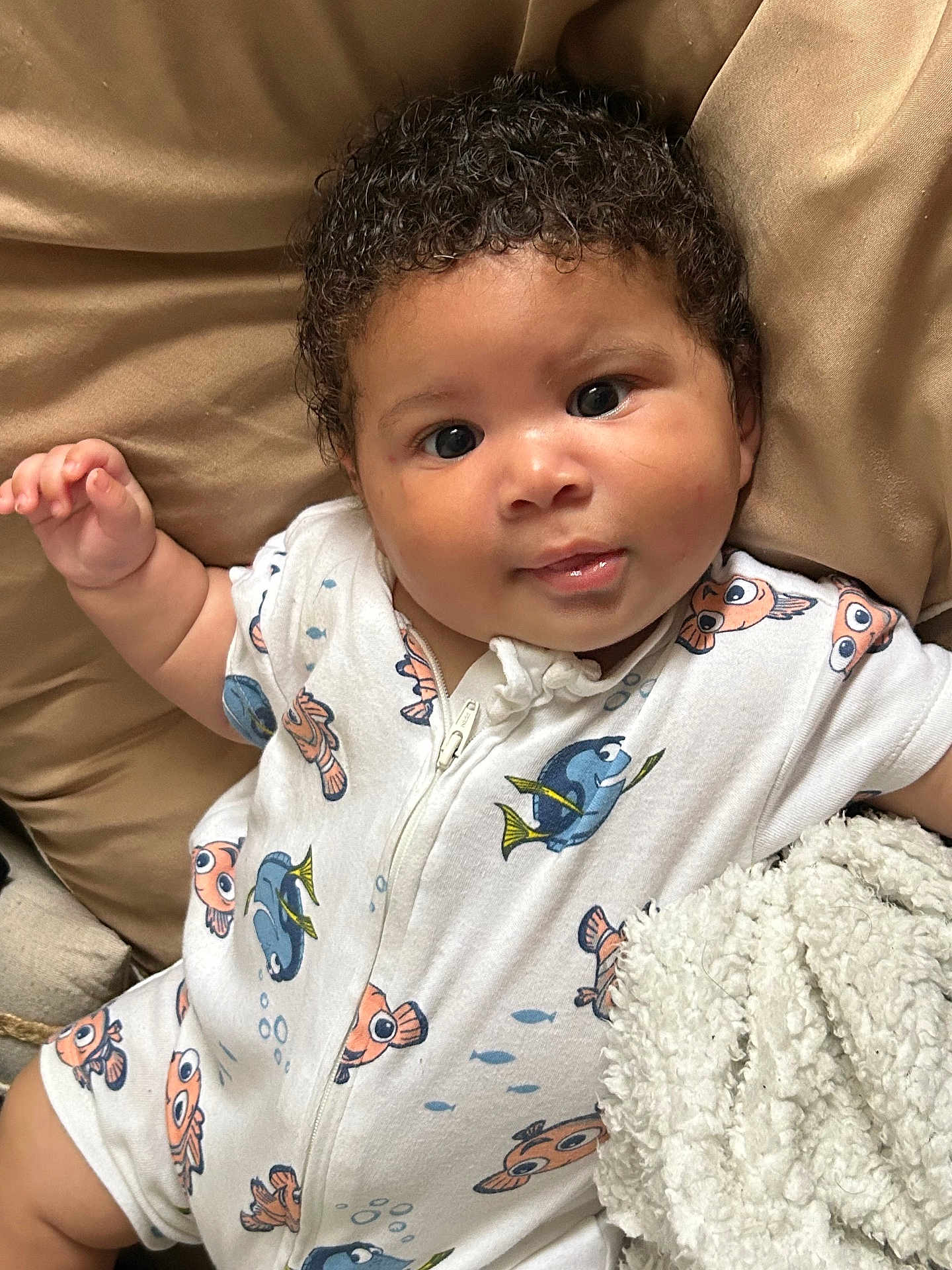 Abel a rejoint le concours — aidez-le/la à gagner de superbes lots ! baby, infant, child, curly_hair, onesie, fish_pattern, blanket, soft_texture, lying_down, cute, face, eyes, smile, skin, hand, portrait, indoors, comfort, clothing, sleepwear
