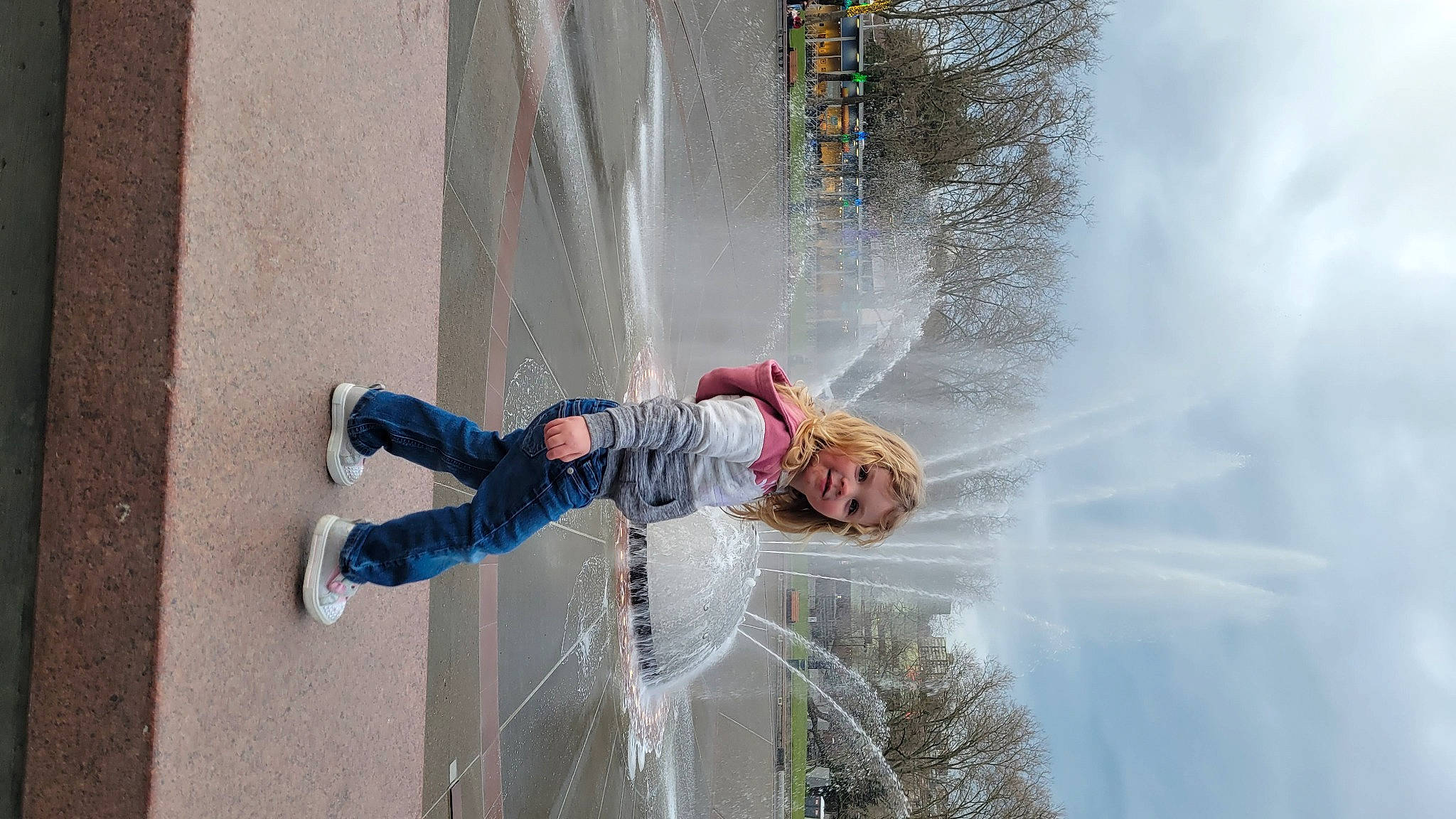 Reya is registered to the contest to win money with this photo: city, fountain, fun, leisure, pedestrian, person, plant, recreation, reflection, street, tree, water, water_feature, window, winter