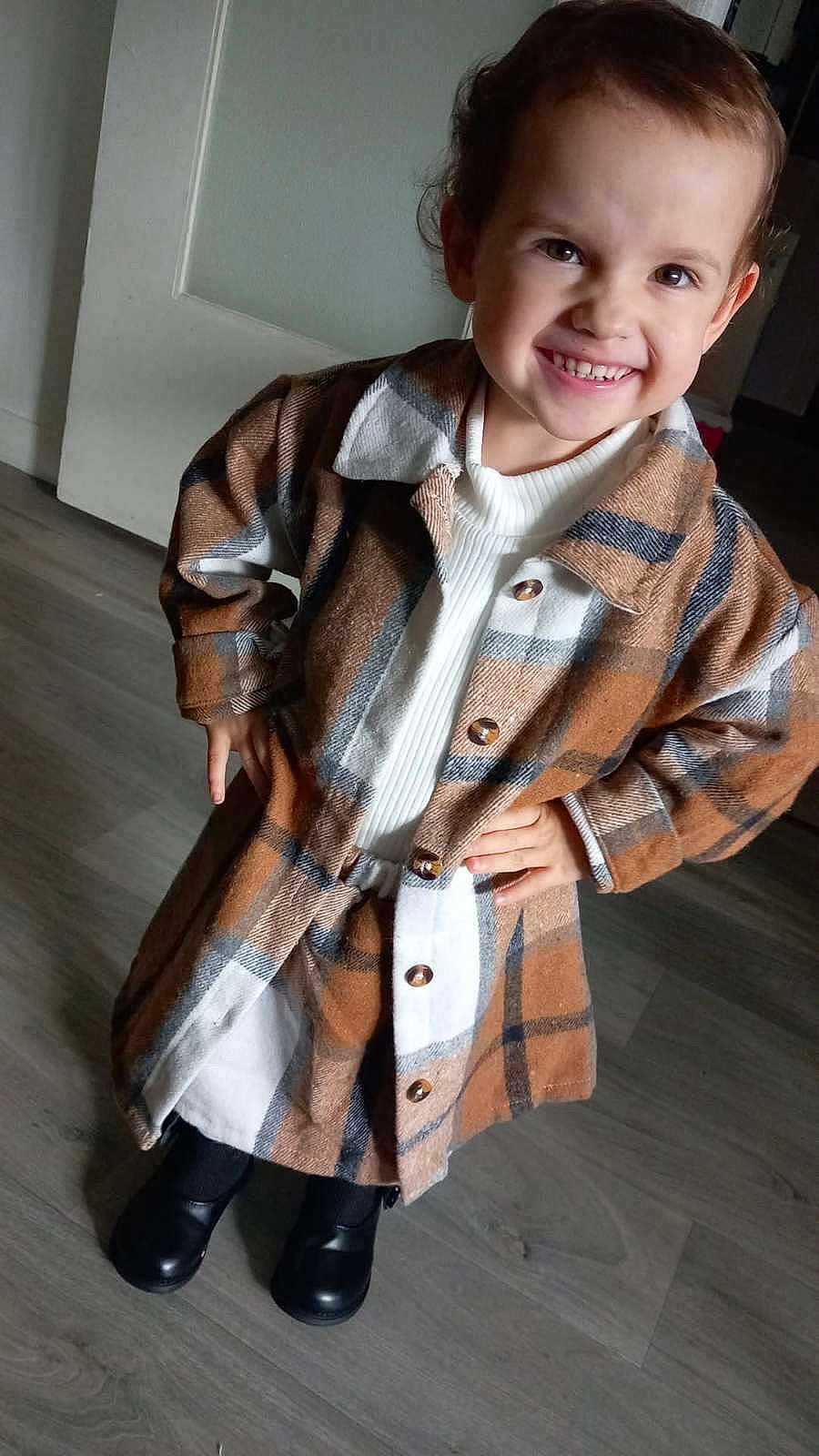 Ruby a rejoint le concours — aidez-le/la à gagner de superbes lots ! child, smile, plaid_coat, white_sweater, black_shoes, wooden_floor, indoor, happy, person, portrait, fashion, cute, standing, hands_on_hips, short_hair, buttoned_coat, warm_clothing, casual, confident, young