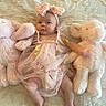 Paisley joined the competition — help win amazing prizes! baby, infant, child, portrait, lying_down, teddy_bear, stuffed_animal, dress, headband, bow, floral, pink, bed, blanket, indoors, face, eyes_open, cute, nursery, fashion