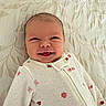 baby, infant, child, smiling, happy, face, portrait, lying_down, bed, bedding, blanket, clothing, cardigan, floral_pattern, knitwear, indoors, cozy, head, eyes, photography