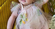 Paisley is registered to the contest to win money with this photo: baby, infant, child, portrait, smiling, happy, headband, bow, dress, floral_dress, flowers, blanket, yellow, lying_down, reaching, outdoor_style, close_up, face, fashion, adorable