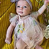 baby, infant, child, portrait, smiling, happy, headband, bow, dress, floral_dress, flowers, blanket, yellow, lying_down, reaching, outdoor_style, close_up, face, fashion, adorable
