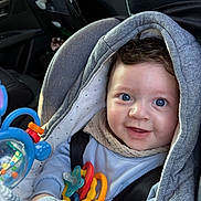 Rafaël a rejoint le concours — aidez-le/la à gagner de superbes lots ! baby, blue_eyes, car_seat, close_up, colorful, cozy, curly_hair, cute, fabric, hand, hooded_jacket, infant, pacifier, playtime, portrait, seatbelt, smiling, teether, toy, transport