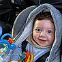 baby, blue_eyes, car_seat, close_up, colorful, cozy, curly_hair, cute, fabric, hand, hooded_jacket, infant, pacifier, playtime, portrait, seatbelt, smiling, teether, toy, transport