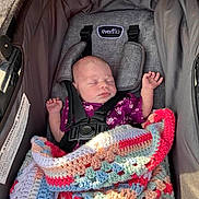 Lilliona is registered to the contest to win money with this photo: newborn, baby, sleeping, stroller, blanket, crocheted_blanket, purple_clothing, infant, child, car_seat, safety_harness, peaceful, resting, indoors, soft_light, cute, small_hands, head, face, cozy