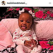 Khalani is registered to the contest to win money with this photo: baby, infant, child, smile, tongue_out, hair_bows, onesie, pajamas, blanket, floral_pattern, leopard_print, pink, pillow, bed, portrait, instagram_screenshot, social_media_ui, story_circles, profile_picture, home_icon