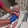 Mckinley is registered to the contest to win money with this photo: newborn, baby, nurse, hospital, medical_equipment, gloves, blanket, diaper, infant, person, human, bed, healthcare, monitor, arm, foot, wrists, tag, skin, care