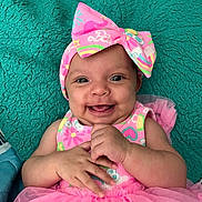 Shyonna joined the competition — help win amazing prizes! baby, smiling, pink_dress, headband, bow, happy, infant, cute, child, portrait, hands, lying_down, teal_blanket, tulle_skirt, colorful_clothing, indoors, skin, face, eyes, person