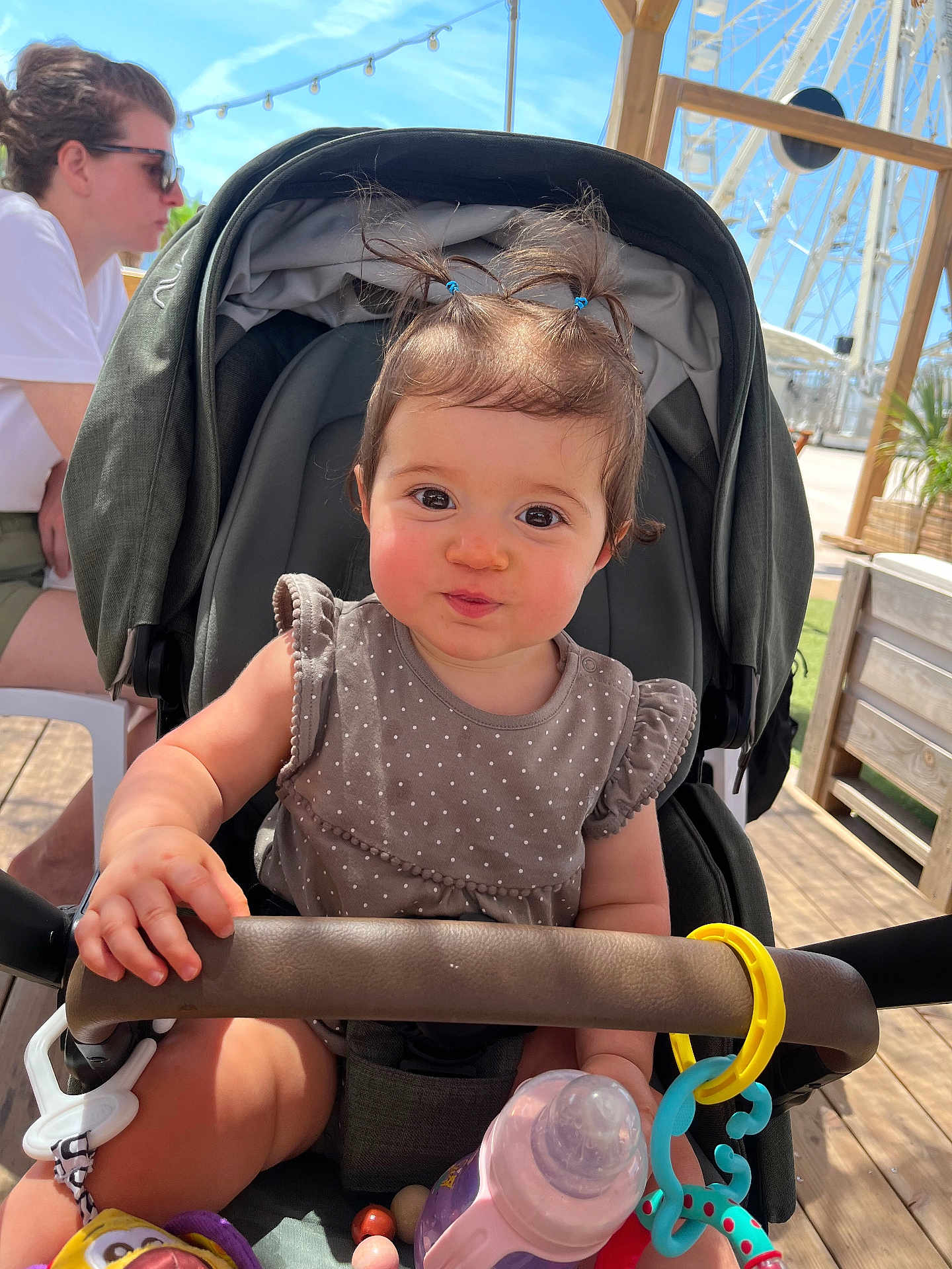 Théa a rejoint le concours — aidez-le/la à gagner de superbes lots ! baby, stroller, toy, bottle, outdoor, child, person, ferris_wheel, wooden_deck, sunlight, hair_ties, clothing, seat, hand, smile, face, playful, casual, adult, sunglasses
