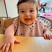 Théa a rejoint le concours — aidez-le/la à gagner de superbes lots ! baby, child, high_chair, messy_face, food, smiling, happy, indoor, table, bib, hand, tongue_out, hair, person, furniture, kitchen, cute, infant, playful, expression