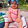 Théa a rejoint le concours — aidez-le/la à gagner de superbes lots ! baby, child, blue_hat, pink_swimsuit, striped_blanket, outdoor, sunlight, garden, greenery, happy, smiling, sitting, barefoot, toddler, summer, nature, wooden_deck, plants, face, cute