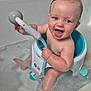baby, bathtub, bath_seat, bath_toy, foam, water, child, smiling, happy, indoor, skin, blue, white, toy, playing, sitting, cute, childcare, cleaning, bath_time