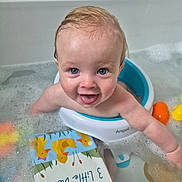 Jaxon is registered to the contest to win money with this photo: baby, bath, bathtub, bubbles, child, blue_eyes, bath_toys, floating_book, happy, smiling, water, wet_hair, skin, foam, playful, seat, infant, indoors, cute, person