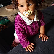 éléa participe au concours pour gagner de l'argent avec cette photo : toddler, child, pacifier, curly_hair, purple_sweater, indoor, couch, television, thoughtful, brown_eyes, necklace, hand, furniture, floor, home, portrait, clothing, baby, cozy, casual