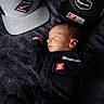 baby, newborn, sleeping, cap, hat, black_clothing, snapon, blanket, infant, portrait, cute, resting, babywear, headwear, logo, branding, soft_texture, closeup, indoor, peaceful