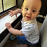 baby, blue_eyes, carpet, child, clothing, curious, face, hand, home, indoor, jeans, light, natural_light, person, short_sleeve_shirt, squatting, toddler, toy, window, young_child