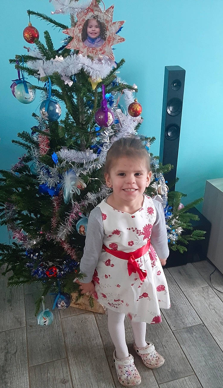Yaël participe au concours pour gagner de l'argent avec cette photo : baby_toddler_clothing, blue, christmas_decoration, christmas_ornament, christmas_tree, event, evergreen, fun, happy, holiday_ornament, joy, ornament, person, photograph, pink, purple, sleeve, smile, snapshot, standing