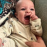 baby, child, infant, smiling, happy, hand, face, fingers, clothing, onesie, patterned_clothing, couch, blanket, texture, indoor, person, portrait, cute, holding, seated