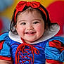 toddler, child, smiling, costume, snow_white, red_bow, headband, blue_dress, red_sleeves, white_collar, portrait, face, happy, cute, indoor, colorful_background, puffy_sleeves, baby, person, closeup
