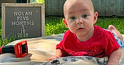Nolan joined the competition — help win amazing prizes! baby, backyard, blanket, child, curious, family_photo, five_months, grass, infant, milestone_board, outdoor, portrait, red_shirt, sitting, smiling, sunlight, tools, toy_truck, workbench, wrench