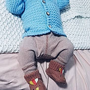 Elliot is registered to the contest to win money with this photo: baby, pacifier, knit_hat, blue_sweater, striped_pants, booties, brown_booties, cute, infant, bed, blanket, cozy, lying_down, looking_up, indoors, child, clothing, soft_texture, warm, comfort