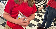 Ellieana joined the competition — help win amazing prizes! background, book, cafeteria, chair, checkered_floor, child, classroom, education, girl, group, indoor, khaki_pants, learning, people, red_shirt, school, smile, students, table, teacher