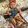 Kaylee is registered to the contest to win money with this photo: baby, bed, blanket, boots, child, clothing, comfort, cute, denim_overalls, floral_pattern, happy, headband, indoors, infant, person, pink_bow, plush_toy, portrait, smiling, socks