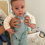 Tom participe au concours pour gagner de l'argent avec cette photo : baby, infant, child, overalls, onesie, hands, adult_hand, holding, face, eyes, surprised_expression, blue_clothing, shoes, towel, blanket, changing_table, phone, nursery, portrait, person