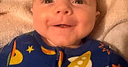 Syrus is registered to the contest to win money with this photo: baby, smiling, face, infant, onesie, space_theme, rocket, stars, planet, blanket, close_up, child, cute, happy, indoors, portrait, soft_lighting, young_child, apparel, sleepwear