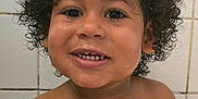 Amadou a rejoint le concours — aidez-le/la à gagner de superbes lots ! child, toddler, curly_hair, smiling, teeth, bathroom, tile_wall, water_droplets, bare_shoulders, happy, cute, face, skin, young_child, indoors, portrait, closeup, person, wet_skin, joyful