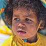 Amadou a rejoint le concours — aidez-le/la à gagner de superbes lots ! child, toddler, face, curly_hair, hat, yellow_clothing, outdoor, sunlight, close_up, portrait, sand, expression, cute, skin, eyes, headwear, summer, daylight, young_child, casual