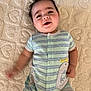 Weston is registered to the contest to win money with this photo: baby, infant, smiling, onesie, striped_clothing, dinosaur_patch, blanket, textured_blanket, lying_down, happy, cute, child, portrait, indoors, skin, face, hand, arm, head, young_child