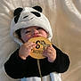 baby, panda_costume, onesie, plush, blanket, wooden_plaque, 6_months, zebra_illustration, child, infant, cute, smiling, hands, face, lying_down, milestone, soft_texture, black_and_white, chewing, indoors