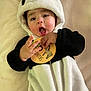 baby, child, panda_costume, onesie, infant, cute, soft_blanket, wooden_sign, zebra_illustration, expression, mouth_open, chubby_cheeks, lying_down, black_and_white, hand, cuddly, portrait, indoors, adorable, young_child