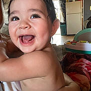 Weston is registered to the contest to win money with this photo: arm, baby, blanket, child, cute, expression, face, fridge, hand, happy, holding, home, indoor, infant, joy, kitchen, person, skin, smiling, toy