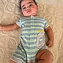 Weston is registered to the contest to win money with this photo: baby, infant, child, romper, clothing, blanket, dinosaur_patch, texture, skin, face, hair, lying_down, cute, chubby, expression, indoors, soft, comfort, casual, newborn