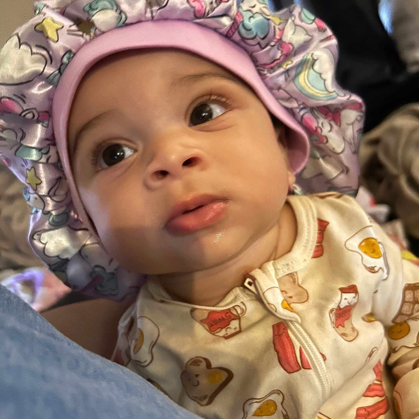 Zaierra is registered to the contest to win money with this photo: baby, bedroom, bonnet, child, closeup, clothing, curious, cute, expression, face, food_pattern, hat, indoor, infant, onesie, person, portrait, sleepwear, soft_lighting, unicorn_pattern