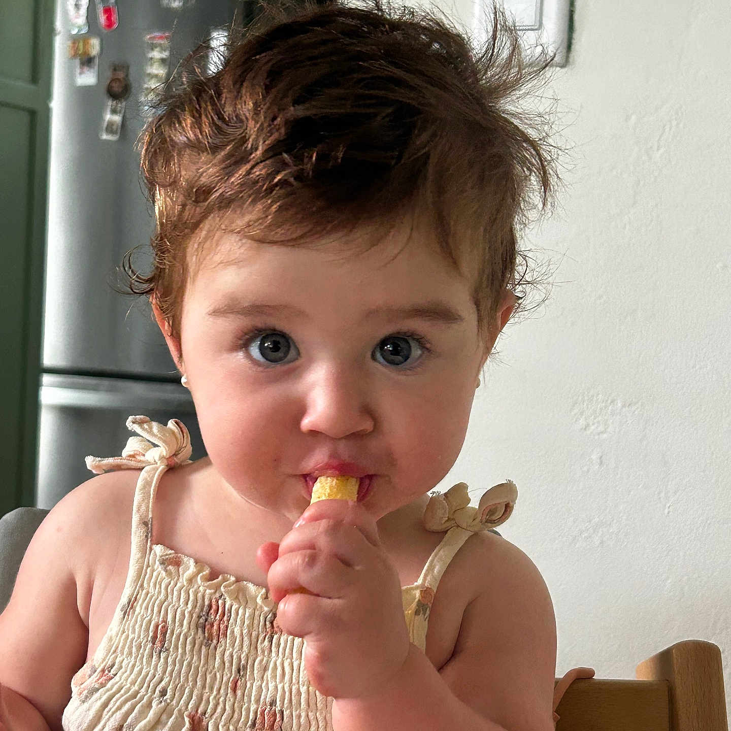 Andrea joined the competition — help win amazing prizes! toddler, child, baby, snack, high_chair, kitchen, brown_hair, blue_eyes, curly_hair, cute, eating, indoor, person, face, clothing, light_switch, refrigerator, furniture, young_child, portrait