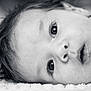 baby, close_up, face, eyes, expression, infant, monochrome, black_and_white, soft_texture, hair, skin, laying_down, portrait, newborn, cute, young_child, innocence, person, head, sleepwear