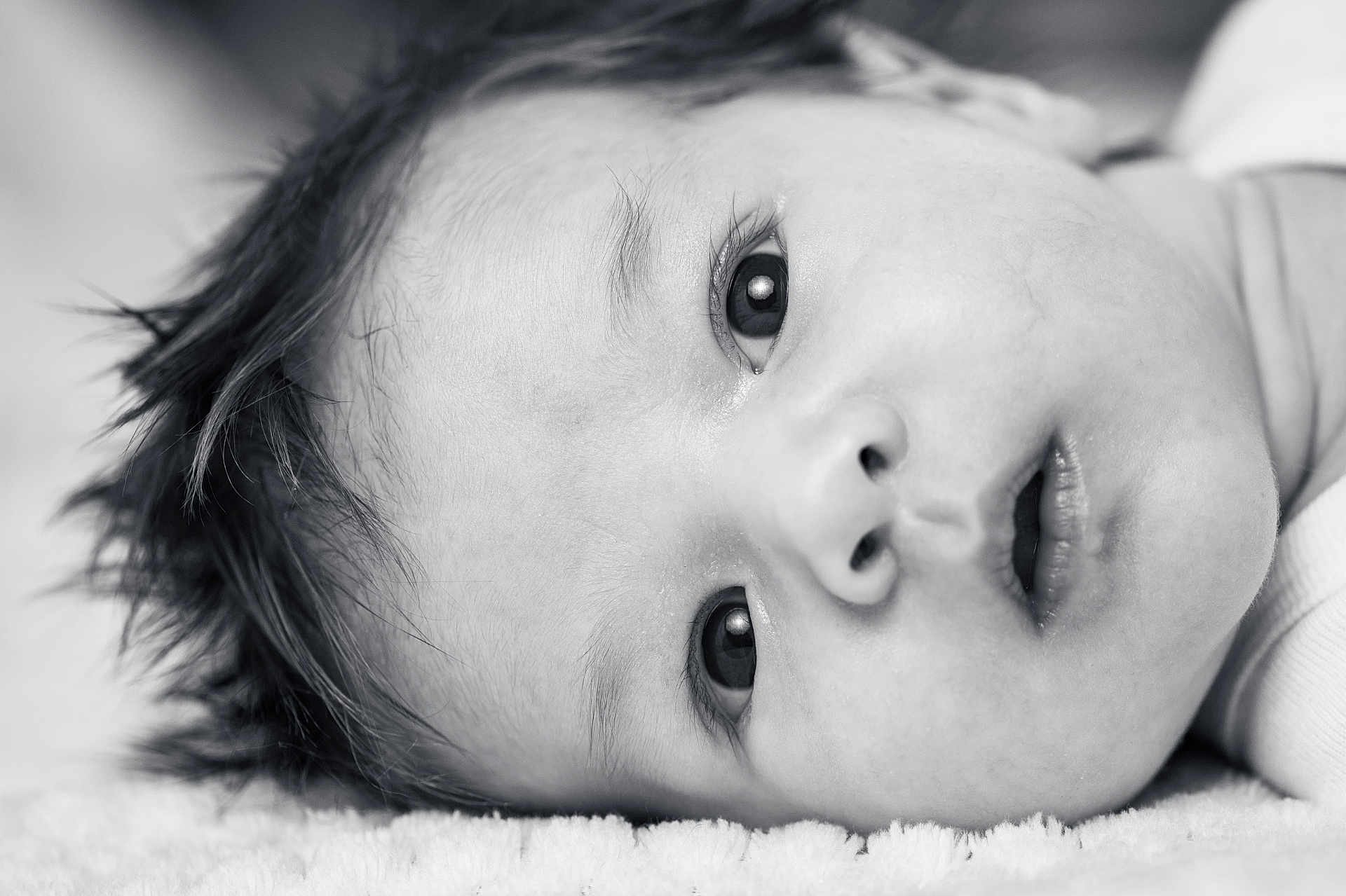 Tim participe au concours pour gagner de l'argent avec cette photo : baby, close_up, face, eyes, expression, infant, monochrome, black_and_white, soft_texture, hair, skin, laying_down, portrait, newborn, cute, young_child, innocence, person, head, sleepwear